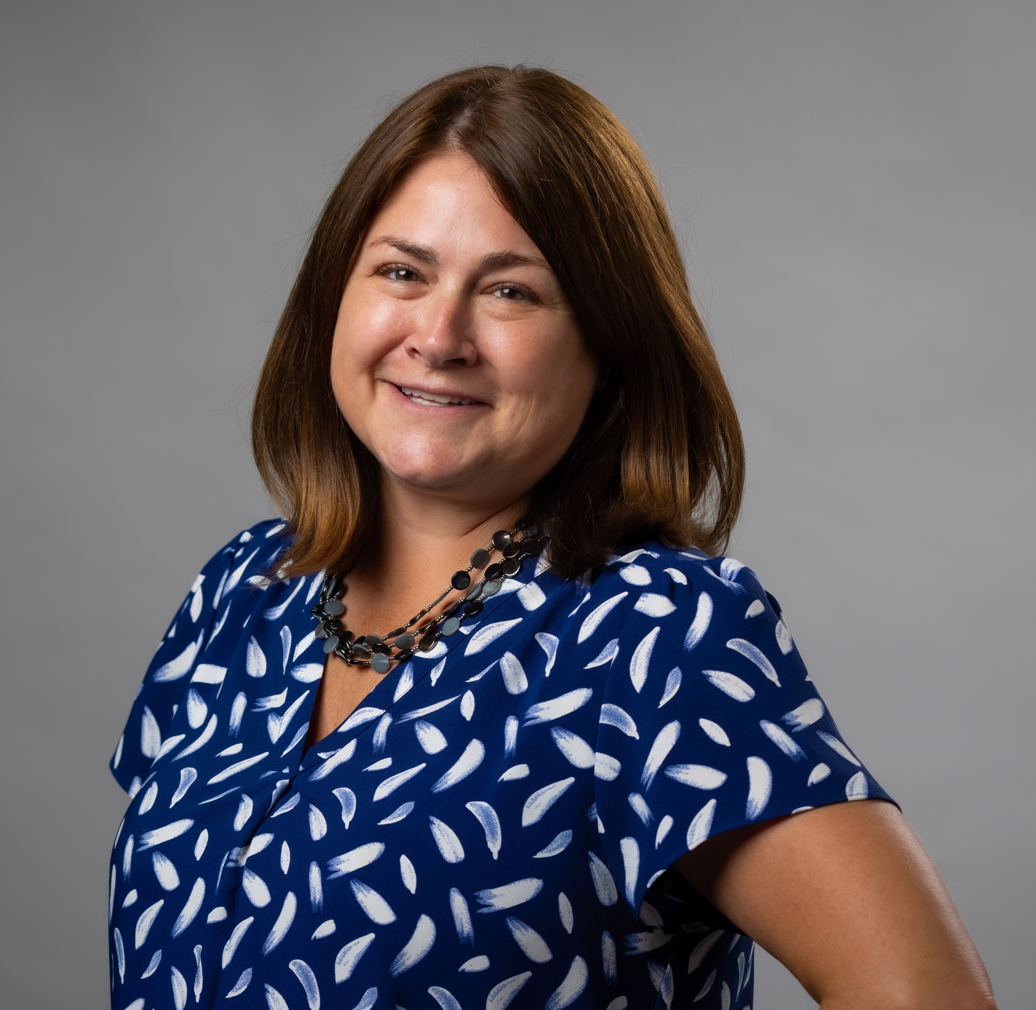 Picture of a woman with brown shoulder length hair in a blue top